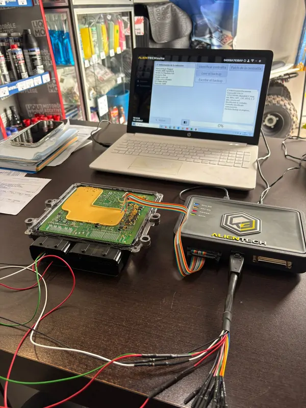 Centralita ECU abierta en banco de trabajo, conectada a equipamiento profesional y a un portátil